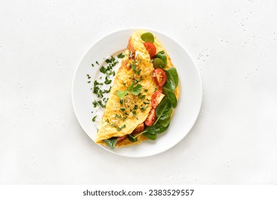 Stuffed omelette with tomatoes and spinach on light stone background. Top view, flat lay