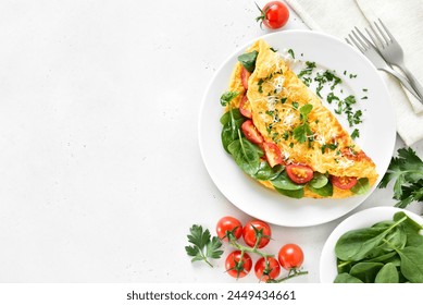 Stuffed omelette with tomatoes and spinach over light stone background with copy space. Top view, flat lay