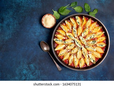 Stuffed pasta shells with spinach and ricotta in a cast iron pan on a blue background. view from above