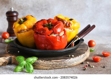Stuffed pepper. Paprika with rice and minced meat. Baked peppers in a cast iron pan on a concrete background. Dinner - Shutterstock ID 2083574026