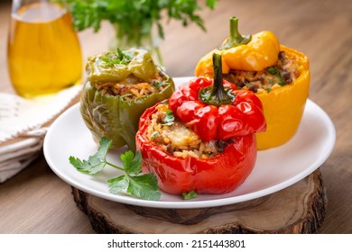 Stuffed peppers, halves of peppers stuffed with rice, dried tomatoes, herbs and cheese in a baking dish on a blue wooden table, top view. Vegetarian dish, stuffed vegetables
