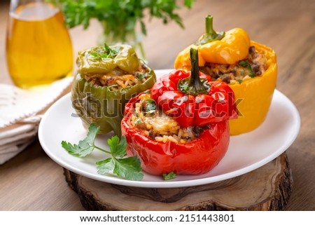 Stuffed peppers, halves of peppers stuffed with rice, dried tomatoes, herbs and cheese in a baking dish on a blue wooden table, top view. Vegetarian dish, stuffed vegetables