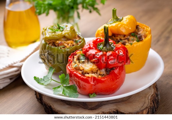 Stuffed peppers,\
halves of peppers stuffed with rice, dried tomatoes, herbs and\
cheese in a baking dish on a blue wooden table, top view.\
Vegetarian dish, stuffed\
vegetables