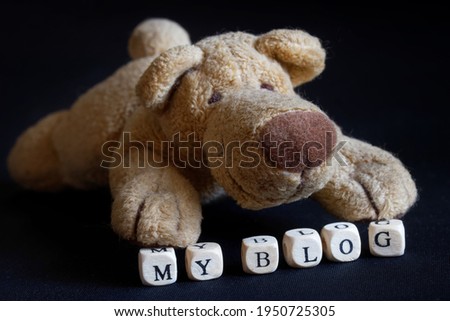 The stuffed plush toy is a friendly dog next to my blog sign. The concept of a blog site for a pet. Black background