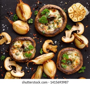 Stuffed portobello mushrooms stuffed with mozzarella and gorgonzola cheese and aromatic herbs on a black background, top view. Vegetarian food