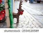 A stuffed reindeer with a red bow is on a cobblestone street