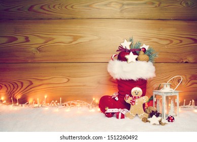 Stuffed Santa Claus Boot With Sweets And Gingerbread Man In The Snow.Cute Rustic Background