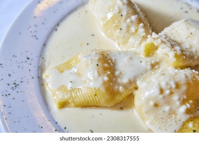 Stuffed shells Italian dish white cream sauce in white bowl on white background food meal plate