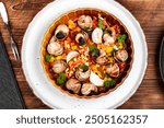 Stuffed snails with butter and greens in baking dish on rustic wooden background. French cuisine