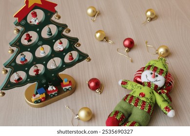 Stuffed snowman and Christmas tree toy on wood background for december holiday celebration. Xmas baubles, decoration for winter season in red and gold colors. - Powered by Shutterstock