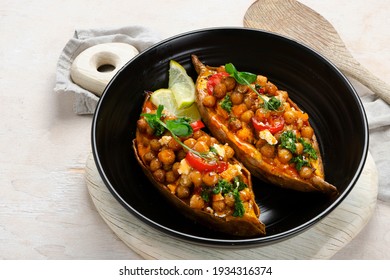 Stuffed sweet potato with spiced chickpea, dressing and herbs. Homemade vegan food concept. Copy space