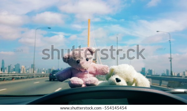 Stuffed teddy\
bear with a dog with a bright\
sky.