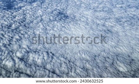 Stunning aerial image capturing the mesmerizing texture of stratocumulus clouds from above. The vast blanket of clouds creates a natural, soft-patterned background, ideal for design and editorial use.