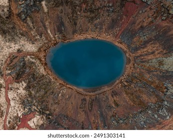 Stunning aerial image of a volcanic crater lake in Iceland, featuring deep blue waters, a reddish-brown rim, and diverse surrounding terrain. - Powered by Shutterstock