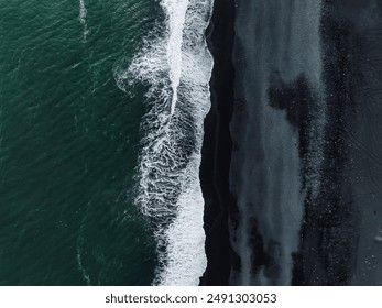 Stunning aerial perspective of Iceland's black sand beach, where white foamy waves crash against the dark shore, creating a striking visual contrast. - Powered by Shutterstock