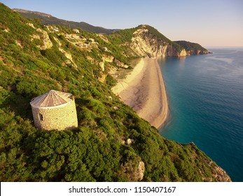 Stunning Aerial Photography Of Famous Milos Beach With An Old Windmill In Front Plan. The Photography Is Taken On Sunset. Lefkada Island - Greece.