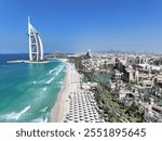 Stunning aerial shot of the iconic Burj Al Arab captured in the afternoon light, showcasing its majestic sail-shaped architecture. The clear skies provide a crisp view of Dubai