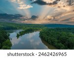 a stunning aerial shot of the still brown waters of the Chattahoochee river surrounded by vast miles of lush green trees with powerful clouds at Roswell Riverwalk Boardwalk in Roswell Georgia	