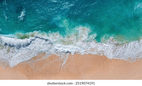 A stunning aerial shot of the turquoise waves gently crashing onto the soft sands of Kelingking Beach, Nusa Penida, Bali. The vibrant colors highlight the serenity and beauty of this tropical paradise - Powered by Shutterstock