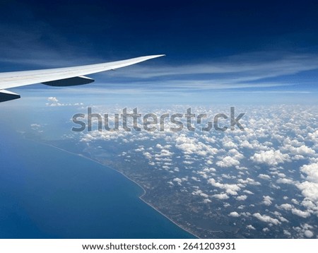 Stunning aerial view from an airplane wing, revealing a vast ocean, cloud formations, and distant land. Ideal for travel, aviation, or nature themes. #AerialPhotography #OceanView #Cloudscape