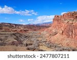 A stunning aerial view of Capitol Reef National Park in the Fruita District orchards, Utah. The image showcases the vibrant red rock cliffs, winding road, and the expansive desert landscape - USA