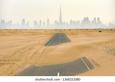 Stunning aerial view of a deserted road covered by sand dunes in the middle of the Dubai desert. Beautiful Dubai skyline surrounded by fog in the background. Dubai, United Arab Emirates. - Shutterstock ID 1368252080