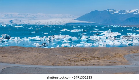 Stunning aerial view of a glacial lagoon in Iceland, featuring floating icebergs on turquoise water and snow-covered mountains in the background. - Powered by Shutterstock
