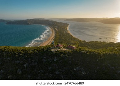 A stunning aerial view of Palm Beach, Sydney, coastal lighthouse at sunset, showcasing the surrounding landscape of beach, ocean, and hills. - Powered by Shutterstock