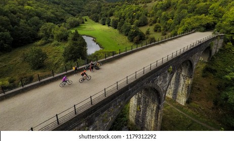 Stunning Aerial View Of People Riding, Cycling Across A Bridge, Viaduct In The Peak District National Park In England, Bakewell, UK