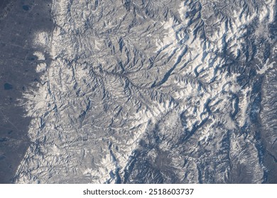 A stunning aerial view of a snowcovered mountain range. The frozen landscape is a mesmerizing display of natures beauty, with frost patterns and shadows. Elements of this image furnished by NASA - Powered by Shutterstock