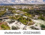 A stunning aerial view of Spokane, WA, featuring Riverfront Park and the Spokane River. The scenic park showcases lush green spaces, historic architecture, and the river running through the city.