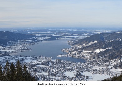 A stunning aerial view of Tegernsee Lake surrounded by snow-covered towns and rolling hills, showcasing Bavaria's picturesque winter charm and tranquil alpine scenery - Powered by Shutterstock