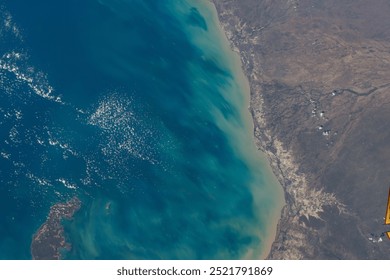 A stunning aerial view of a tropical island with pristine beaches, turquoise waters, and crashing waves. The vibrant blue ocean stretches out to the horiz. Elements of this image furnished by NASA - Powered by Shutterstock