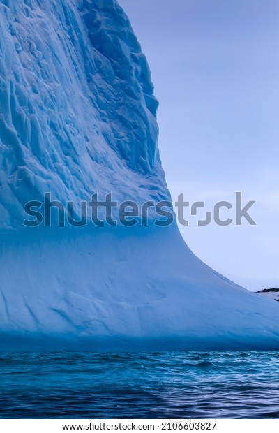 Stunning Antarctic scenery detail of a\
beautiful blue ice cliff of a blue iceberg from a melting tidewater\
glacier floating in the icy blue water off the Antarctic Peninsula\
coast of Polar\
Antarctica