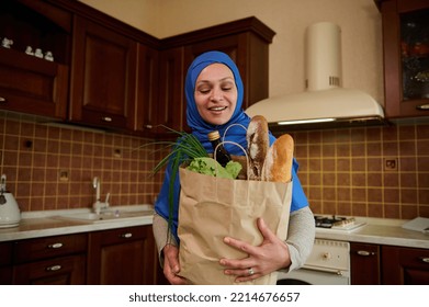 Stunning Arab Muslim Woman Housewife With Her Head Covered In Blue Hijab, Arriving Home With An Eco Paper Shopping Bag Full Of Groceries And Healthy Food. Home Food Delivery. Healthy Eating