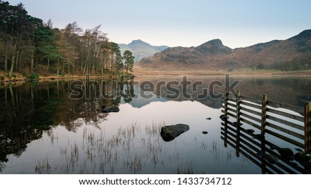 Stunning Autumn Fall vibrant sunrise over Blea Tarn in the Lake District with High Raise and The Langdales in the distance