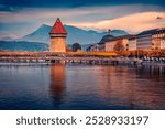 Stunning autumn view of famous old wooden Chapel Bridge (Kapellbrucke), landmark 1300s wooden bridge with grand stone water tower. Pictureasque evening cityscape of Lucerne town, Switzerland.