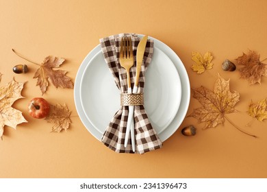 Stunning autumn-themed table decor concept. Top view of plates, cutlery, dry autumn leaves, checkered napkin, pumpkin, acorns on pastel brown background - Powered by Shutterstock