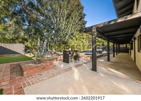 Stunning backyard featuring a sparkling pool, lush greenery, and an outdoor lounge area for relaxation