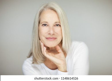 stunning beautiful and self confident best aged woman with grey hair smiling into camera, portrait with white background