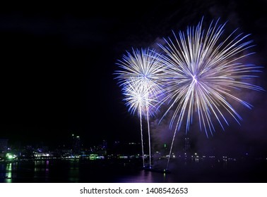 Stunning blue and white fireworks exploding into the night sky over the bay