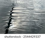 A stunning, calm sea showing a black skiff rowing boat oar reflection in the silky water. Beautiful highlights from the natural light. A perfect background or cover.