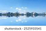 Stunning Cityscape Reflected in Serene Water Under a Vast Blue Sky  