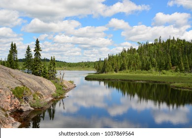 Stunning Clear Reflection Of A Beautiful Landscape With Rocks And Tall Fir Trees On A Quiet Lake In Ontario, Canada.