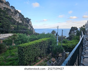 The stunning cliffsides of Capri showcase colorful buildings nestled among vibrant flowers, creating a picturesque scene. Lush greenery cascades down the rocky faces, enhancing the island's natural be - Powered by Shutterstock