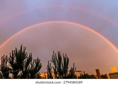 Stunning double rainbow in dramatic sunset sky over city buildings