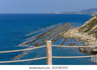 A stunning expanse of azure waters meets rugged rock formations, creating a picturesque coastal landscape under a clear sky. The tranquility of the afternoon invites exploration. - Powered by Shutterstock