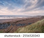 Stunning Fanore beach in county Clare, Ireland. Popular travel and tourist hotspot with amazing Irish nature scenery view. Sandy beach with rocks, powerful ocean with waves and dramatic sky.