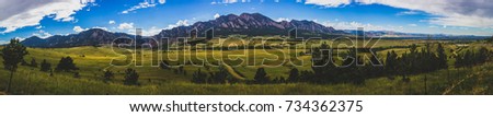Stunning Flatirons mountain and valley with winding road on a summer day with blue sky and clouds, Boulder, Colorado