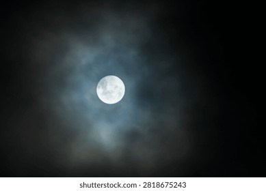 Stunning full moon shining through dramatic dark clouds at night.
Bright full moon with a mystical blue halo surrounded by soft night clouds.